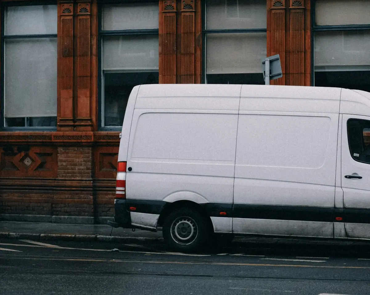 Side of a plain white work van parked on a city street